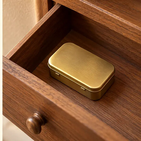 The closed gold-tone tin stored neatly in an open wooden drawer